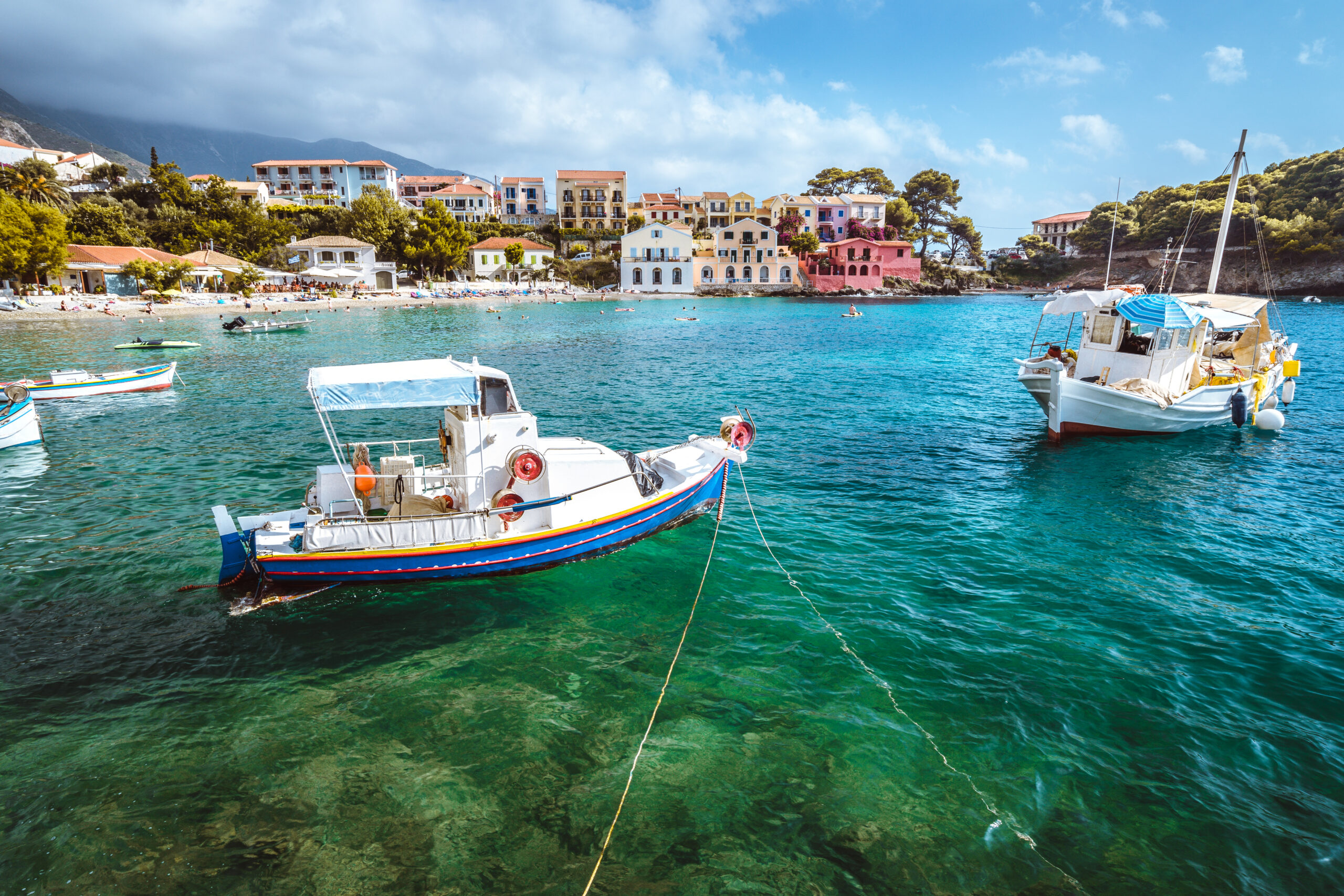 Assos village on Kefalonia island, Greece. White blue local boats at anchor in the emerald rippled sea water bay Alaska