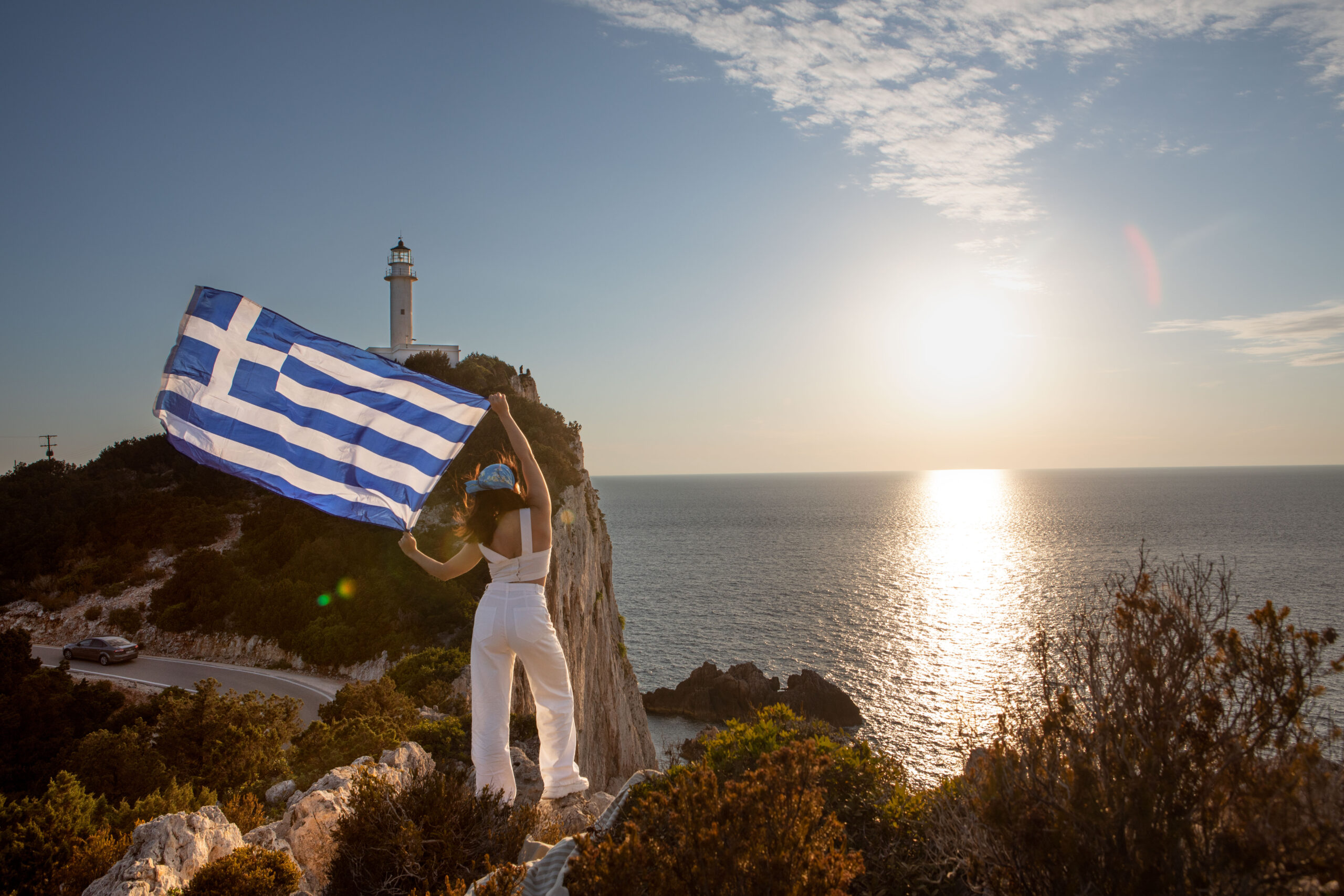 woman with greece flag looking at sunset above the sea Rome